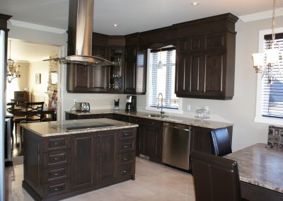 Armoires de cuisine en érable teintes brunes foncées ainsi qu’un comptoir en granite.