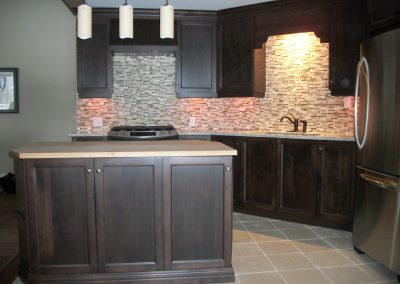 Armoires de cuisine en bois merisier teintes, centre des portes plaqué, ainsi qu’un comptoir en granite.